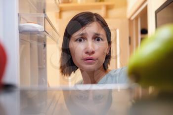 Pretty asian Woman Looking For Food In Refrigerator. healthy food concept. the idea of overeating and delaying stress in quarantine.