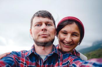 Happy couple taking selfie self-portrait photo hiking. Two friends or lovers on hike smiling at camera outdoors mountains. a beautiful multiracial couple of hipster
