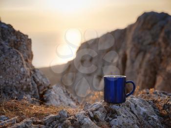 Closeup photo of cup with tea over out of focus mountains view. Trekking concept