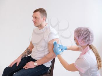 FEMale doctor holding syringe making covid 19 vaccination injection dose in shoulder of male patient. Flu influenza vaccine clinical trials concept, corona virus treatment side effect