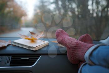 Woman feet in warm socks on car dashboard . The concept of freedom of movement. Autumn Weekend.