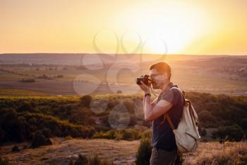 Man photographer with backpack and camera taking photo of sunset mountains Travel Lifestyle hobby concept adventure active vacations outdoor