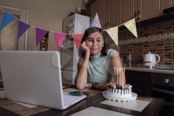 woman celebrating birthday online in quarantine time. Woman celebrating her birthday through video call virtual party with friends. Authentic decorated home workplace. Coronavirus outbreak 2020.