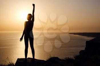 silhouette of woman with raised hands on the beach at sunset. People success, victory, and power. Strong woman, Winning, success , and life goals concept.