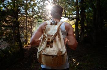 Man Traveler with backpack hiking outdoor in summer sunset forest. Travel Lifestyle and Adventure concept.