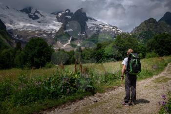 Man with backpack hiking in mountains. Travel Lifestyle success concept, adventure active vacations outdoor , mountaineering sport in North Caucasus, Dombai, Karachay-Cherkessia, Russia