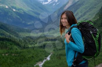 Backpacker on top of a mountain enjoying valley view. wanderlust travel concept, space for text, atmospheric epic moment. Image for trekking, hiking or climbing. North Caucasus, Dombai,, Russia.