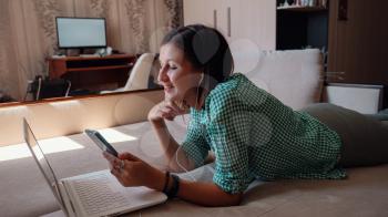 Young attractive woman on sofa working on new project with laptop in home. Attractive businesswoman studying online, using laptop software, web surfing information or shopping in internet store.