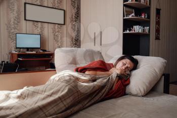 Sick and Flu Woman. Caught Cold. Woman feeling cold with blanket resting on the sofa at home
