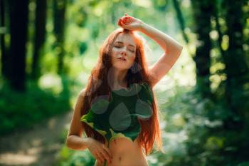 Protection of the environment, rescue of plants and nature. A young ginger woman stand in the green fairy forest. Idea and concept of Arbor day or Mother earth day