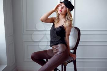 Young blonde in a silk blouse and leather pants poses against a white wall. catalog beauty salon party. idea and concept of health, youth and proper self-care