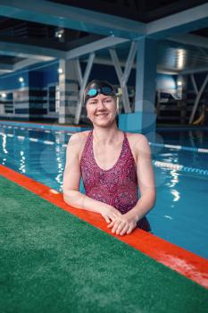 Happy muscular swimming woman wearing glasses and cap at swim pool and represent health and fit concept, idea of sport, healthy lifestyle and leisure