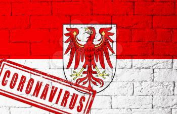 Flag of the regions of Germany Brandenburg with original proportions. stamped of Coronavirus. brick wall texture. Corona virus concept. On the verge of a COVID-19 or 2019-nCoV Pandemic.