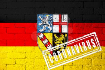 Flag of the regions of Germany Saarland with original proportions. stamped of Coronavirus. brick wall texture. Corona virus concept. On the verge of a COVID-19 or 2019-nCoV Pandemic.