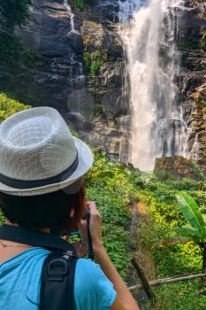 tourist Woman take photo of Wachirathan Waterfall at Doi Inthanon National Park, Mae Chaem District, Chiang Mai Province, Thailand. Mobile photo