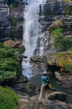 tourist Woman take photo of Wachirathan Waterfall at Doi Inthanon National Park, Mae Chaem District, Chiang Mai Province, Thailand. Mobile photo
