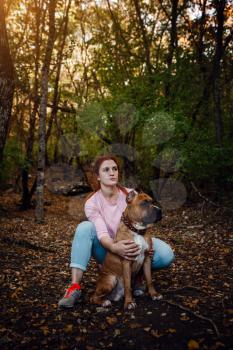redhaired woman with her dog have fun on the walking. idea and concept of free time, happiness, care and freedom, long walks in the forest