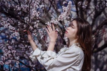 young asian woman in a flowering garden. romantic image of stylish casual woman , trendy silk blouse. positive mood. Cheery Blossom full bloom in Japan.
