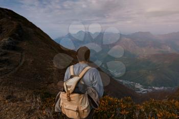 Young male hipster in the mountains in autumn. Discovery Travel Destination Concept. Tourist on the high rocks background. Sport and active life concept.