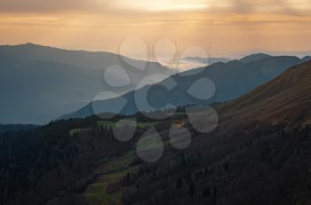 Autumn in the North Caucasus, Rosa Khutor ski resort in off-season. Russia, Sochi. Vintage toning. Travel background. Landscape with sun light shining through orange clouds and fog.