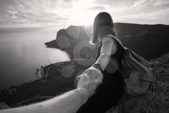 Girl standing on the mountain top over blue sea view. Follow me - POV. Couple enjoying a hike in nature. The concept of the journey to the meeting of new discoveries