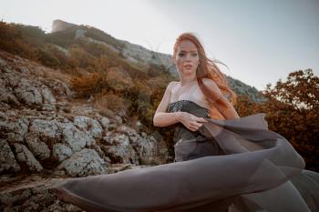 beautiful furious scandinavian warrior ginger woman in grey dress with metal chain mail. Woman is a Viking. Fantasy. Book Cover. beautifully flying dress