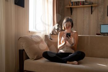 Young woman isolating at home and relaxing: stay at home social media campaign for coronavirus prevention. communication with a cat, calm and poise