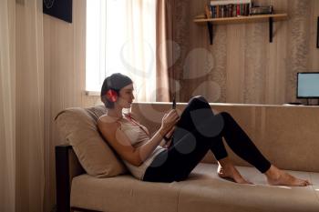 Young woman isolating at home and relaxing: stay at home social media campaign for coronavirus prevention. chatting with friends and using apps on a smartphone