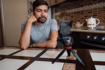 Young man having video call via smartphone in the home office. Virtual house party. confident young guy vlogger influencer shooting social media video blog talk at home