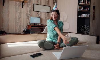 Girl celebrating birthday online in quarantine time through video call virtual party. Coronavirus outbreak 2020. Woman Holding Glass of Wine
