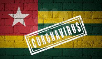 Flag of the Togo on brick wall texture. stamped of Coronavirus. Corona virus concept. On the verge of a COVID-19 or 2019-nCoV Pandemic. Novel Chinese Coronavirus outbreak
