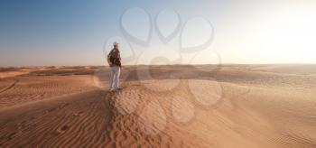 Desert adventure. Young man with backpack walking on sand dune. The ghost town of Al-Madam near Dubai, United Arab Emirates. idea and concept of success and achieving a goal