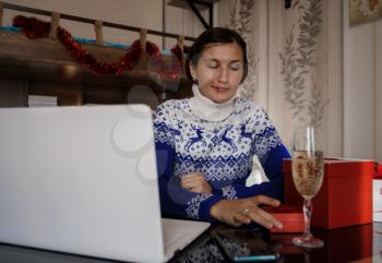 Happy asian woman wearing blue sweater holding glass of champagne, talking with family, social distance friend by video conference call meeting chat at home. stay home vocation, Christmas party online