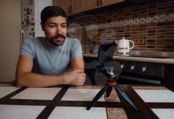 Young man having video call via smartphone in the home office. Virtual party. confident young guy vlogger influencer shooting social media video blog talk at home