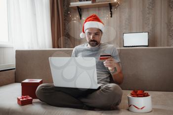Christmas online shopping, sales and discounts promotions during the Christmas holidays, online shopping at home and lockdown coronavirus. Man shopping for xmas gifts online