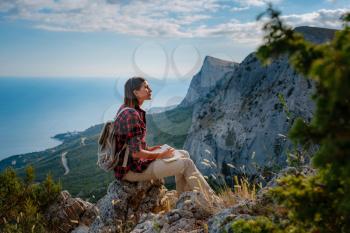 woman hiker enjoy the view at mountain peak cliff, writes notes, ideas in his paper notebook. idea of ecotourism travel. Discovery Travel Destination Concept
