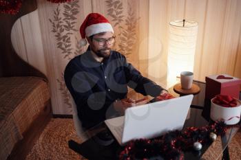 Virtual Christmas day house party. Man smiling wearing Santa hat Business video conferencing Online team meeting video conference calling from home.