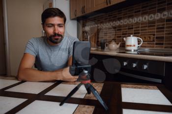 Young man having video call via smartphone in the home office. Virtual house party. confident young guy vlogger influencer shooting social media video blog talk at home