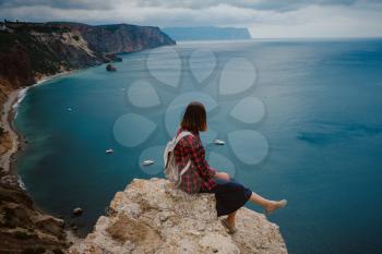 woman traveling with backpack tourist on seashore in summer. Enjoying Beautiful clouds sky among Mighty Cliffs Meeting Ocean. the idea and concept of freedom, vacation and discovery