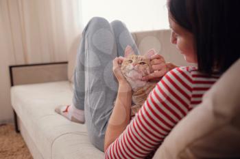 woman relaxing with her ginger tabby cat on a sofa. Cosy scene, hygge concept. Animals and lifestyle