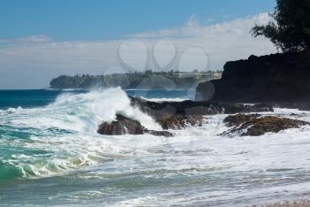 Waves crash onto Lumahai beach with St Regis hotel in background on Kauai Hawaii