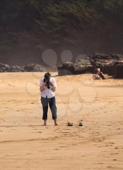 Senior caucasian woman taking photo of the beach with camera