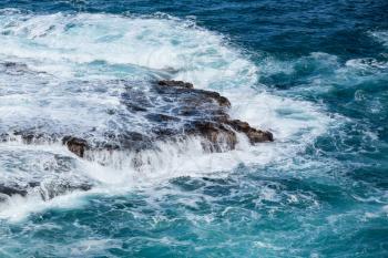 Strong sea waves flow over lave rocks on edge of the shore near Lumahai Beach, Kauai, Hawaii
