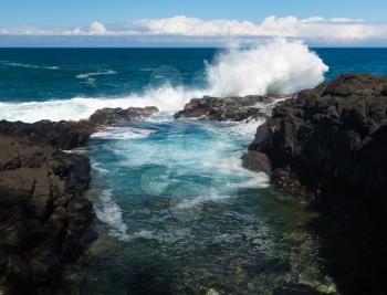 Waves crash into narrow gully that forms Queens Bath at Princeville, Kauai, Hawaii