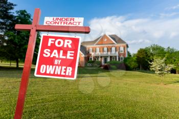 For Sale and Under Contract realtor sign in front of large brick single family house in expansive grass yard for real estate opportunity