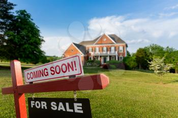 For Sale and Coming Soon realtor sign in front of large brick single family house in expansive grass yard for real estate opportunity