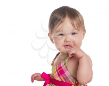 Isolated head and shoulders of caucasian ethnicity baby girl one year old facing the camera and sucking finger while giving cute smile