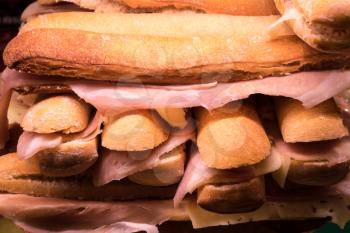 Stack of ham and cheese french bread sandwiches on food counter in Spanish market in Madrid