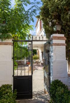 Gate and pathway to  courtyard under veranda of a boutique hotel with table and chair set for afternoon drinks