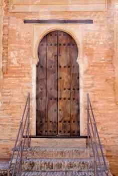 Simple wooden doorway with ornate arch in gardens of Alhambra palace Granada, Spain